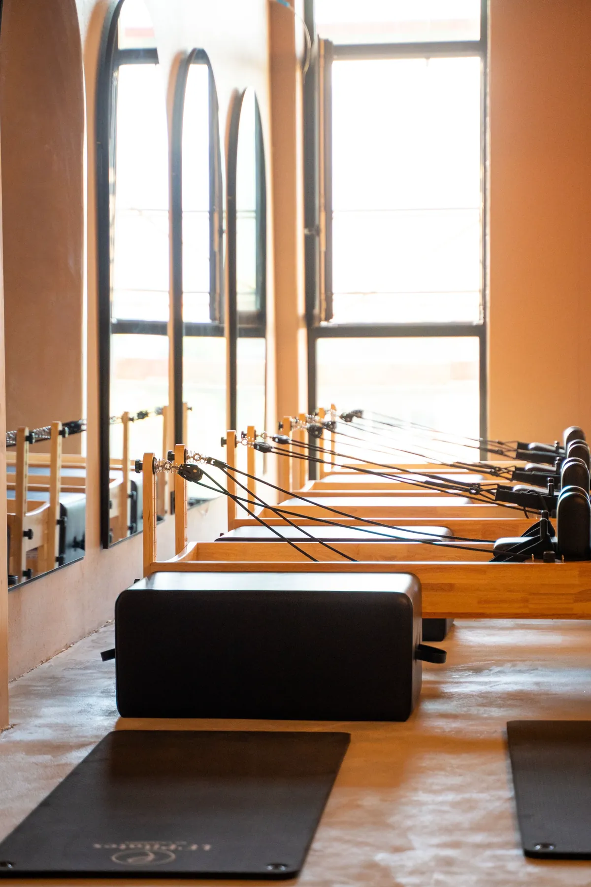 Rangée de Reformers face aux fenêtres, studio Pilates du Jura