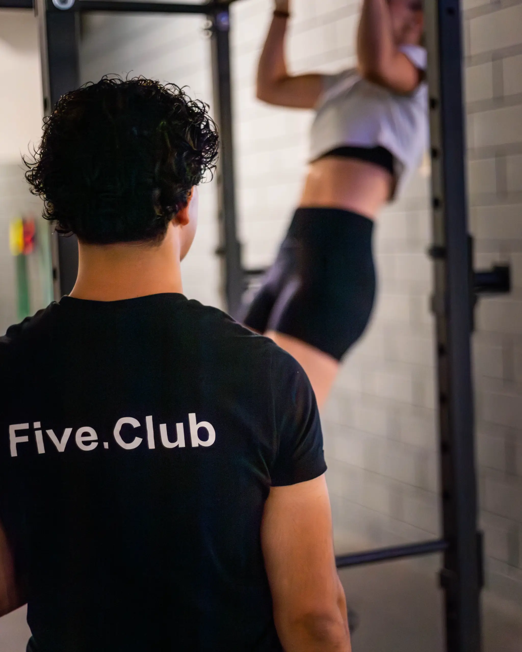 Un coach Five.Club accompagne une membre à la barre de traction